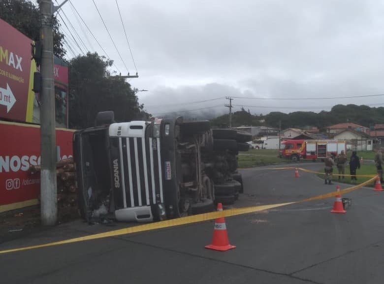 Carreta carregada de madeira tomba e vazamento de combustível precisa ser contido