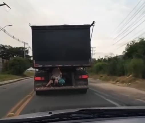 Menino é flagrado sentado em para-choque de caminhão em rodovia movimentada