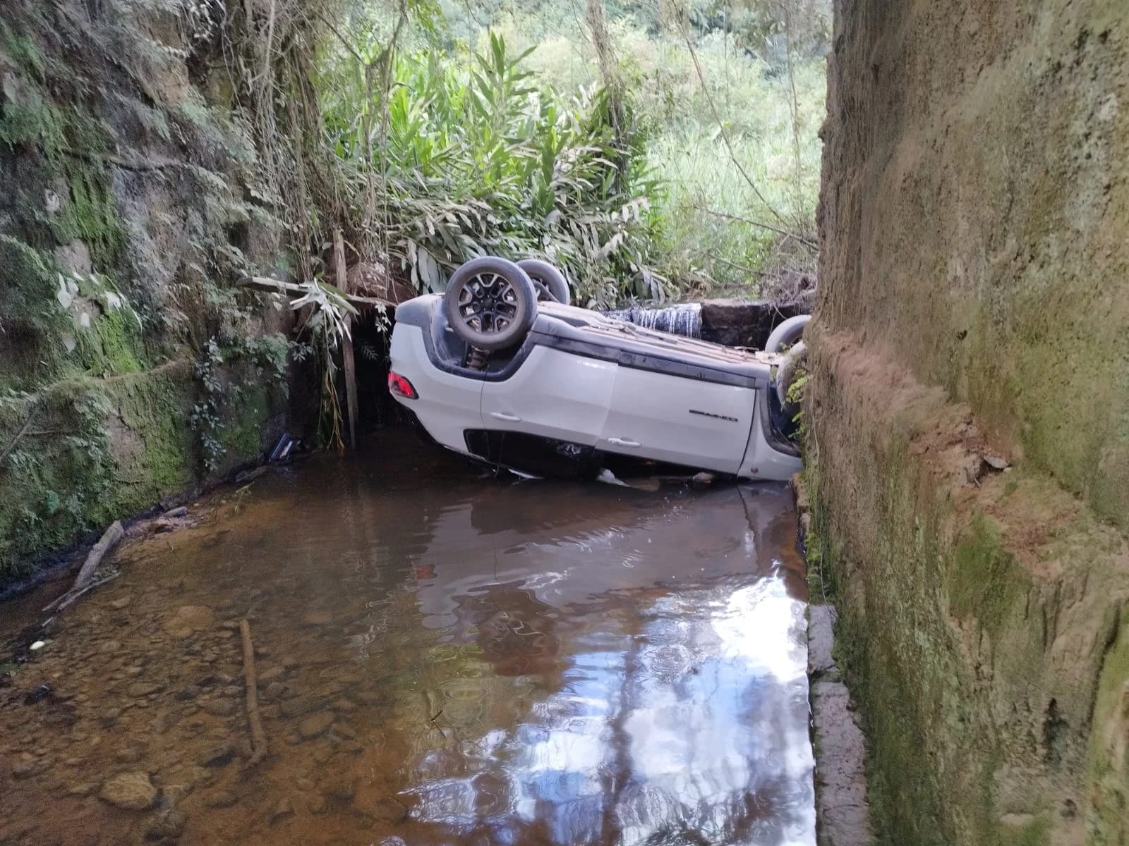 Carro sai da pista e cai em rio após despencar de barranco